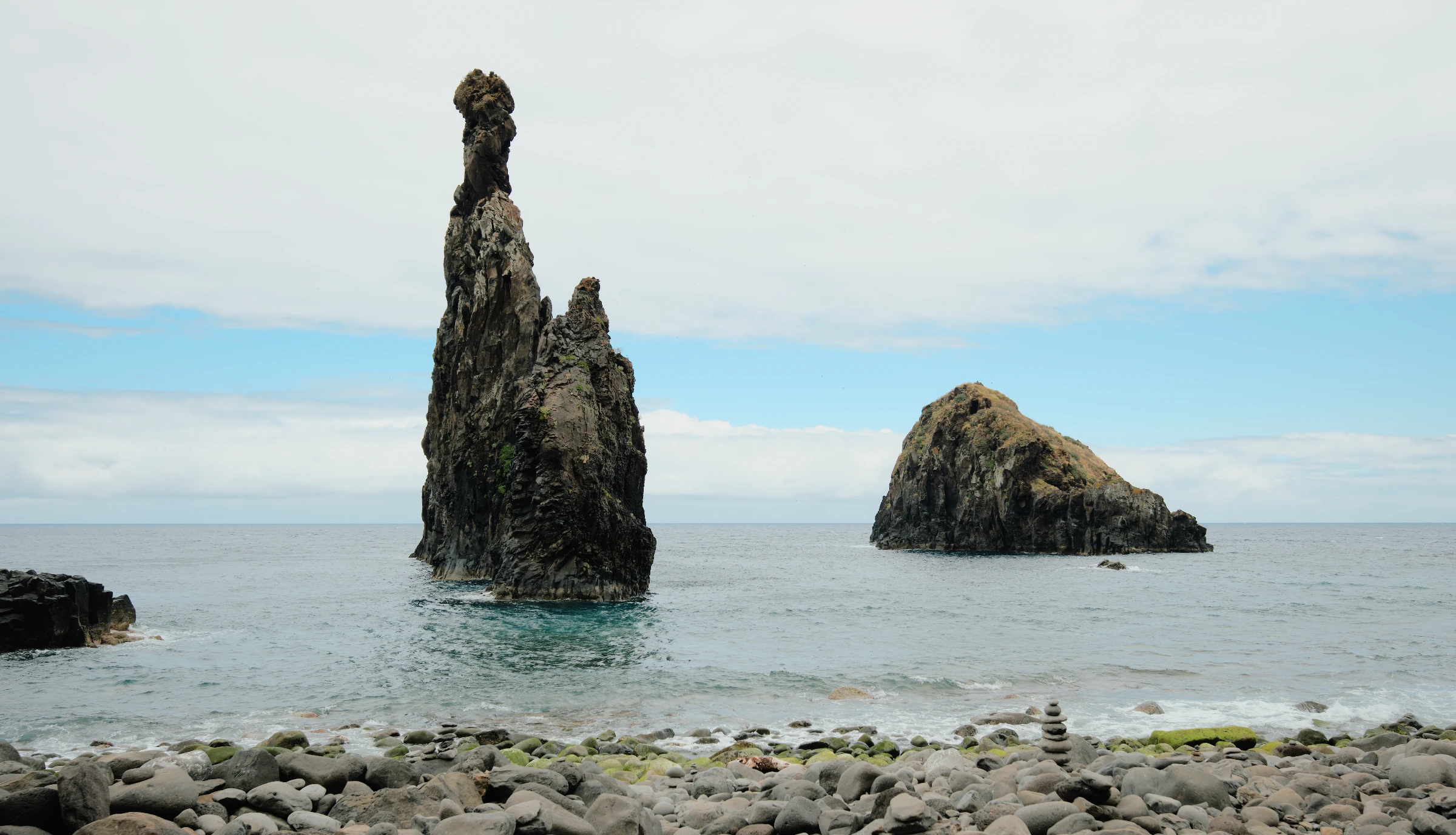 Two sea stacks above blue-green water, developed from a Fujifilm RAW with the sea horizon straightened